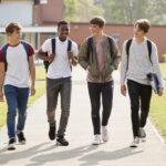 group of male teenage students walking around college campus