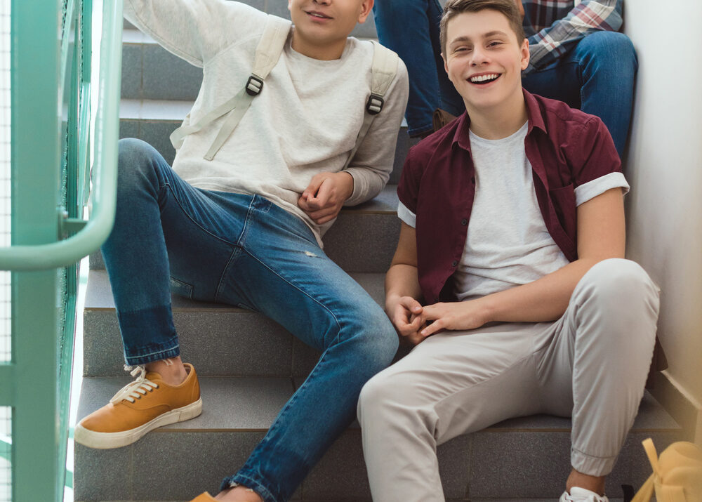 teenage schoolboys sitting on stairs at school and looking at camera